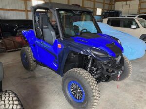 Blue off-road utility vehicle with rugged tires parked indoors.
