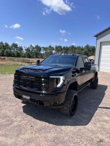 Black lifted pickup truck parked near a building on a sunny day.