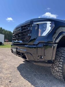 Close-up of a black off-road truck's front end with rugged tires.