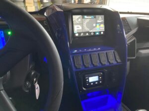 Dashboard of a vehicle showing control switches and a screen.