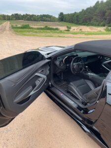 Interior view of a sleek black car with the driver's door open.