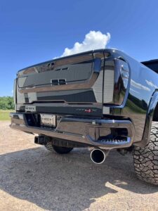 Rear view of a shiny black pickup truck with large tires and dual exhaust pipes.