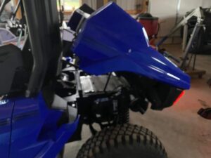 Close-up of a blue off-road vehicle focused on the front section and tire.