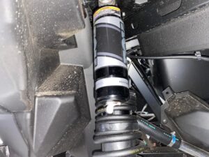 Close-up of a vehicle's suspension system showing a coilover and shock absorber.
