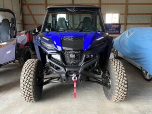 Blue off-road vehicle parked indoors with large tires and winch.