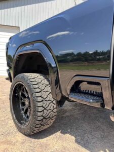 Close-up of a rugged tire and fender on a black off-road vehicle.