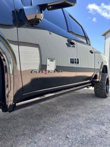 Shiny black truck with reflections and 'Cummins' badge on the door.
