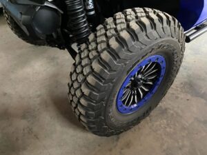 Close-up of an off-road tire with deep treads and blue rim accents.