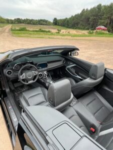 Interior view of a modern convertible car with black leather seats and dashboard.