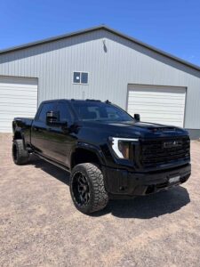 Black lifted pickup truck parked in front of a metal building.