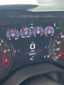 Car dashboard showing speedometer at zero and various gauges.