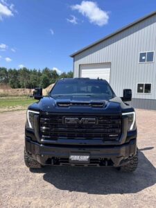 Front view of a black GMC truck parked outdoors near a building.