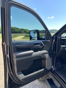 Open car door showing interior and side mirror with a scenic road view.