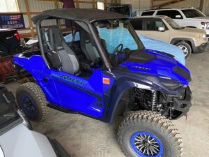 Blue off-road dune buggy parked indoors with rugged tires.