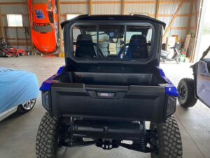 Rear view of a lifted off-road vehicle with large tires in a garage.