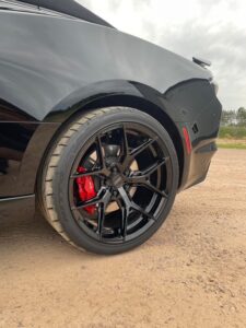 Close-up of a black sports car wheel with red brake calipers.