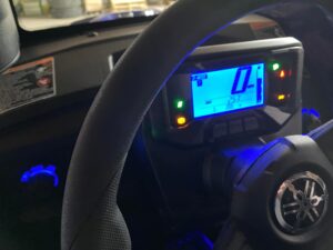 Close-up of a car dashboard and steering wheel with illuminated digital display.
